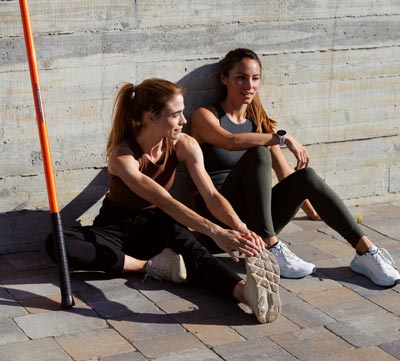 Two women stretching with a Stick Mobilty Training Stick